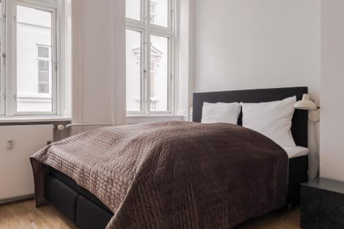a bedroom with a bed and two windows at Perfect Apartments in Superb Location by Strøget, the Metro & Attractions in Copenhagen