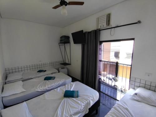 a room with three beds and a window at Hotel XV in Piracicaba