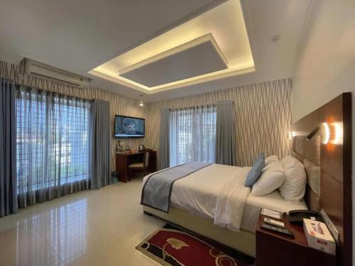 a bedroom with a bed and a desk and windows at Nascent Gardenia Residence in Dhaka