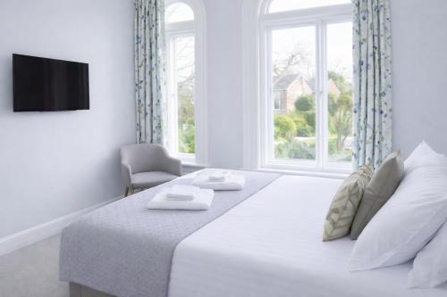a white bedroom with a large bed and a window at The Milford Arms in Hounslow