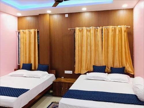 two beds in a room with yellow curtains at Roy Guest House in Kānki