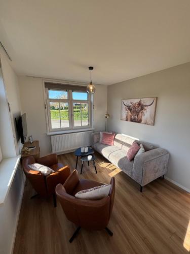a large living room with a couch and chairs at Sint Anthonijshoek in Koudekerke