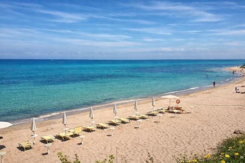 a beach with chairs and umbrellas and the ocean at Hotiday Castelsardo Spiaggia in Castelsardo