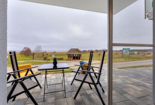 a patio with two chairs and a table and a view of a field at Haus Achterwasserblick 1 in Loddin