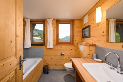 a bathroom with a tub and a toilet and a sink at Chalet François in Champéry