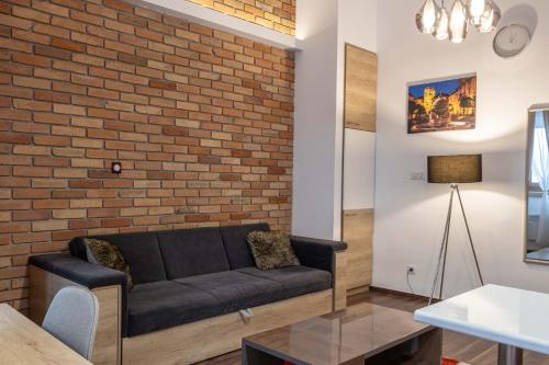 a living room with a couch and a brick wall at City Royal Studio in Székesfehérvár