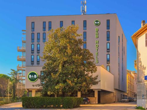 a building with a tree in front of it at B&B HOTEL Fabriano Janus in Fabriano