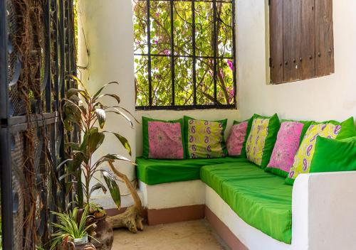 a green couch in a room with a window at Ella's Swahili Villa - Restored 1840s Heritage Home in Bagamoyo