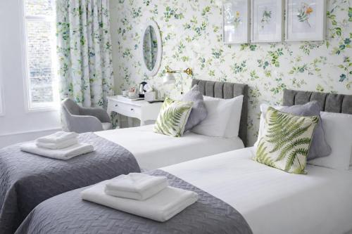 a bedroom with two beds and a desk with a mirror at The Milford Arms in Hounslow