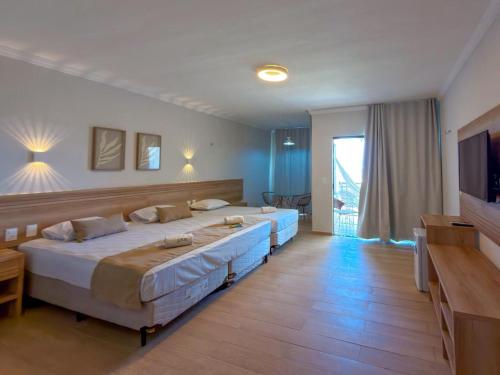 a bedroom with two beds and a flat screen tv at Jangadeiro Praia Hotel Resort - Parque Aquático e Pé na Areia in Aquiraz