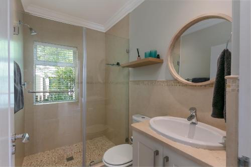 a bathroom with a shower and a sink and a mirror at SL9 - Pezula Double Storey Luxury in Knysna