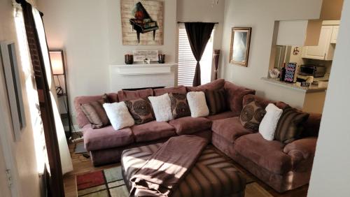 a living room with a brown couch with pillows at Cozy 2 Bedroom Townhome in Addison in Addison