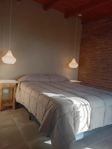 a bedroom with a large bed and two pendant lights at Complejo DOS LUNAS in San Roque