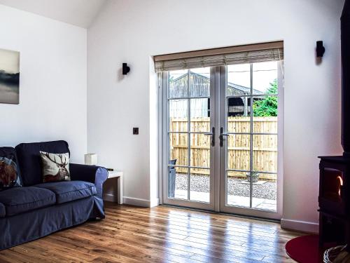 a living room with a couch and a sliding glass door at Rubys Cottage in Crieff