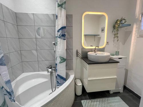 a bathroom with a tub and a sink and a mirror at Le Mazet au Lavandou in Le Lavandou