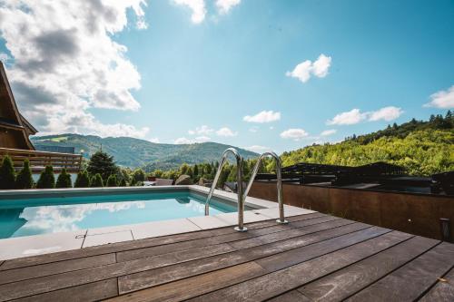 a swimming pool on a deck with mountains in the background at Niebo Beskidu in Brenna