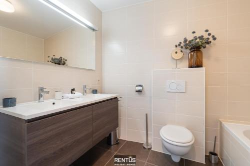 a bathroom with a sink and a toilet and a tub at Maison Beluga - spacious apartment in Westende in Middelkerke