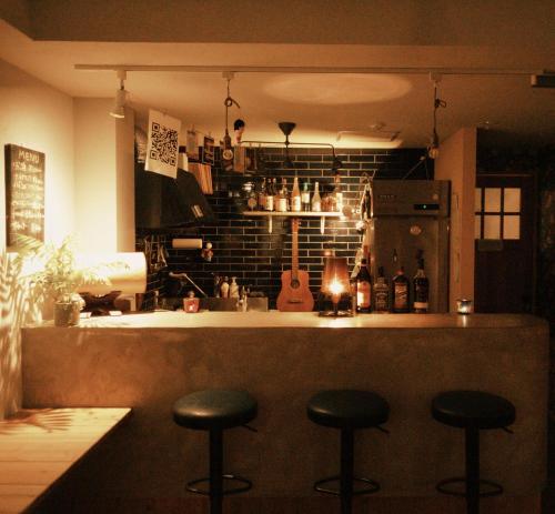 a kitchen with three stools at a bar with a guitar at Ten to Sen Guesthouse in Takamatsu