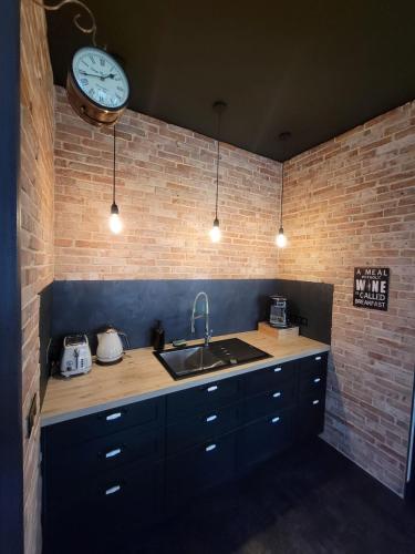 a kitchen with a sink and a clock on a brick wall at Le Loft Des Arts in Thonon-les-Bains