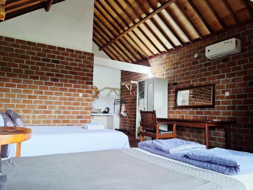 a bedroom with two beds and a brick wall at Bunga Maliq Bungalow Lombok in Tetebatu