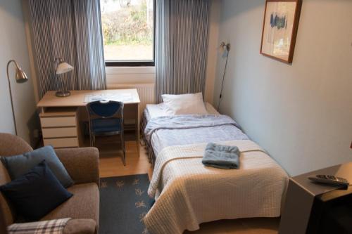 Cette chambre comprend deux lits, un bureau et une chaise. dans l'établissement Gasthaus Mikkeli, à Mikkeli