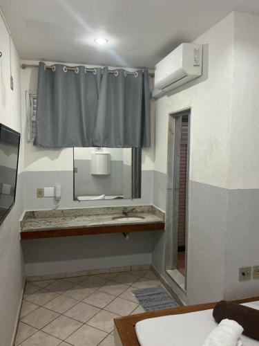 a bathroom with a sink and a mirror and a shower at Hotel Angely in Belo Horizonte