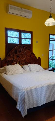 a bedroom with a large wooden bed with white sheets at Jacque's Beachside Hostel in Progreso