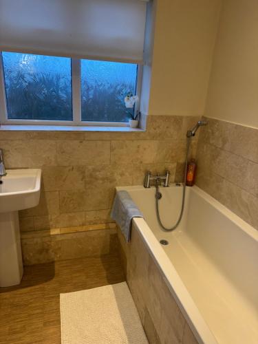 a bathroom with a tub and a sink and a window at Oakham ridge in Mansfield