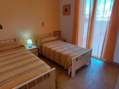 two beds sitting in a room with a window at 023 e 024 Tulipano di SalentoInVacanzaCOM in Torre Pali