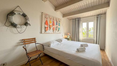 een slaapkamer met een bed, een stoel en een raam bij Charmante villa face à la mer ! in La Flotte