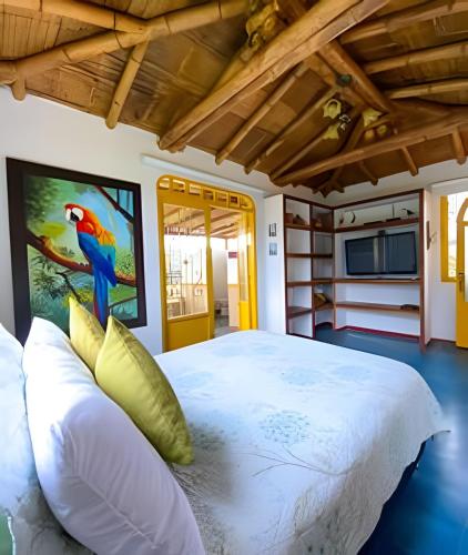 a bedroom with a large white bed with a parrot on the wall at FINCA HOTEL DON JULIO in Santa Rosa de Cabal