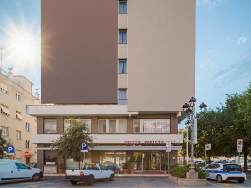 un gran edificio con coches aparcados en un aparcamiento en B&B HOTEL Riviera Celle Ligure, en Celle Ligure