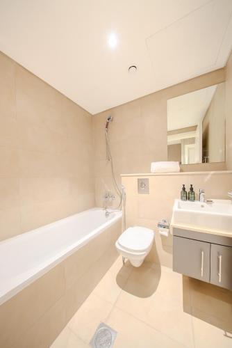a bathroom with a tub and a toilet and a sink at 3BR Amazing Villa - Private Pool - 3WC - BBQ Pit in Sharjah