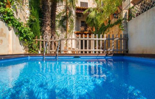 a blue swimming pool with a fence and trees at La Casa De Los Espejos in Capdepera