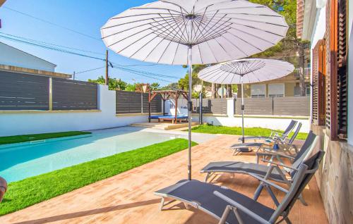 a patio with two chairs and an umbrella next to a pool at Sa Gola in Canyamel