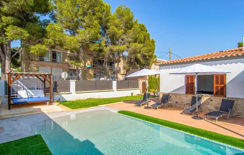 a swimming pool with chairs and umbrellas next to a house at Sa Gola in Canyamel