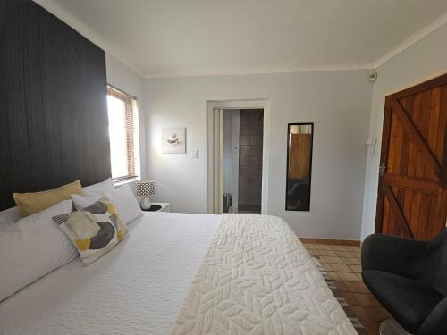 a bedroom with a large white bed with a wooden door at 22 On Schwester Frieda in Swakopmund
