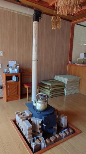 a room with a stove with a pot on the floor at 白神山地の麓でヤギのいるゲストハウス　あわじ商店 in Fujisato