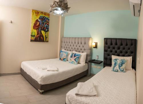 a bedroom with two beds and a painting on the wall at Art Hotel Getsemani in Cartagena de Indias