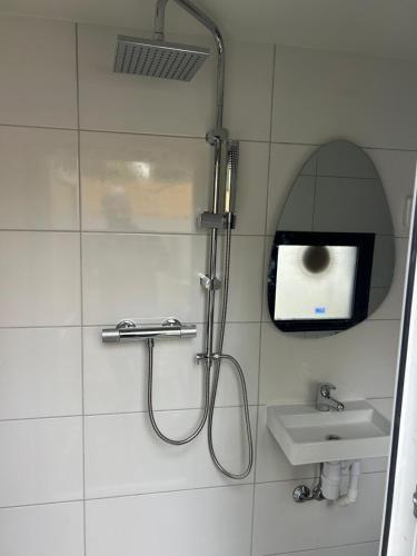 a bathroom with a shower and a sink and a tv at Tiny House Beachroom in Scheveningen