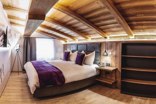 a bedroom with a large bed and wooden ceilings at Chalet Amadeus by we rent in Piesendorf