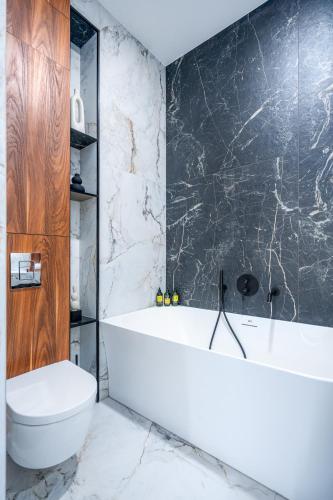 a bathroom with a white tub and a toilet at Nad Zatoką Apartament 132 by Warmia4Rent, przy samej plaży miejskiej in Olsztyn