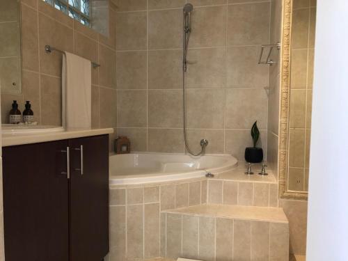 a bathroom with a bath tub and a sink at Spacious sunny secure and central with scenic views in Hout Bay
