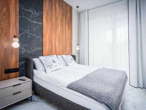 a bedroom with a bed with white sheets and a window at Nad Zatoką Apartament 132 by Warmia4Rent, przy samej plaży miejskiej in Olsztyn