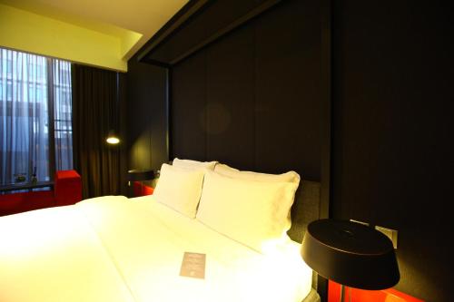 a bedroom with a white bed and a black wall at Hotel Lainn in Kaohsiung