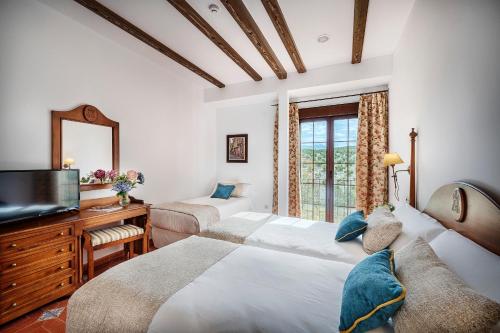 a bedroom with two beds and a tv and a mirror at Beneste Cazorla Hotel in Cazorla