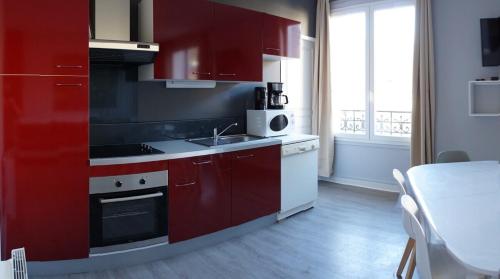 a kitchen with red cabinets and a sink at LILOA in La Bourboule