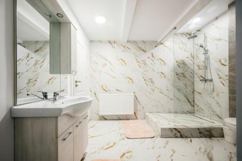 a white bathroom with a sink and a shower at Căsuța din Vale in Voronet