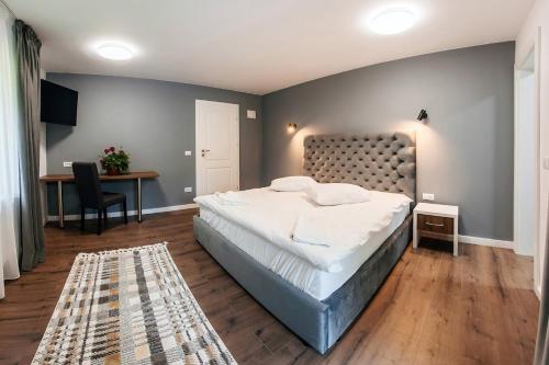 a bedroom with a large bed and a desk and a table at Căsuța din Vale in Voronet