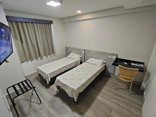 a hospital room with two beds and a tv at Hotel Avalon Maringá Econômico in Maringá